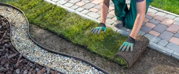 jardinier en train de poser un rouleau de gazon